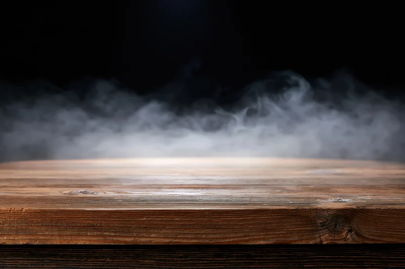 Rustic wooden tabletop with wispy smoke in dark background