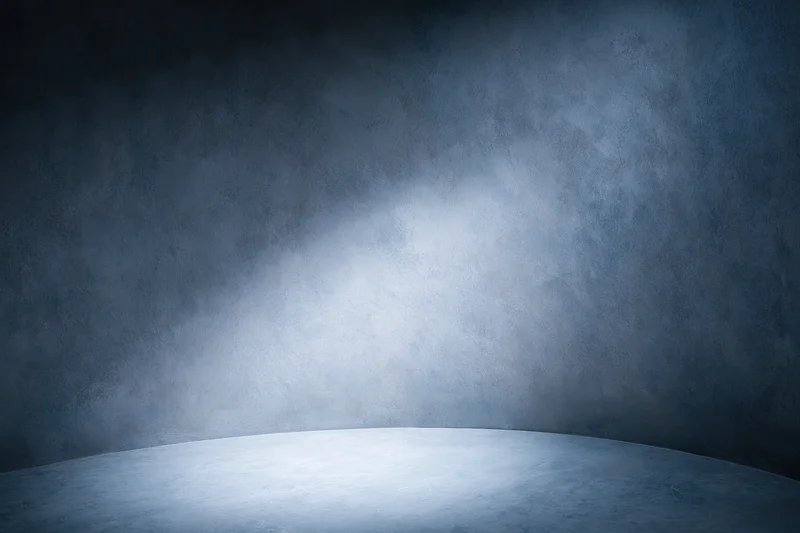 Curved seamless studio backdrop with spotlight on textured concrete wall and floor
