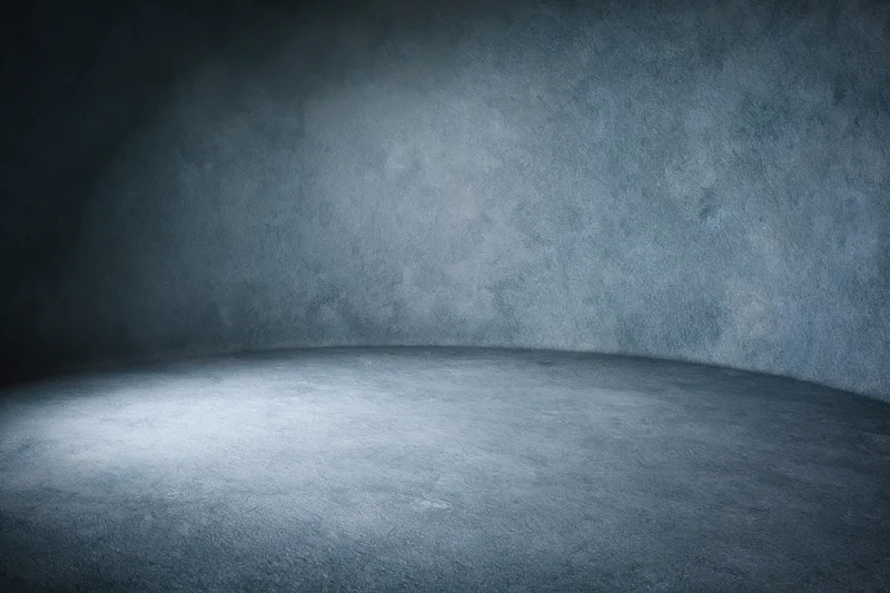 Empty curved studio backdrop with spotlighted center and dark textured walls
