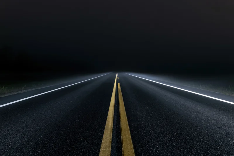 Empty asphalt road stretching into darkness at night