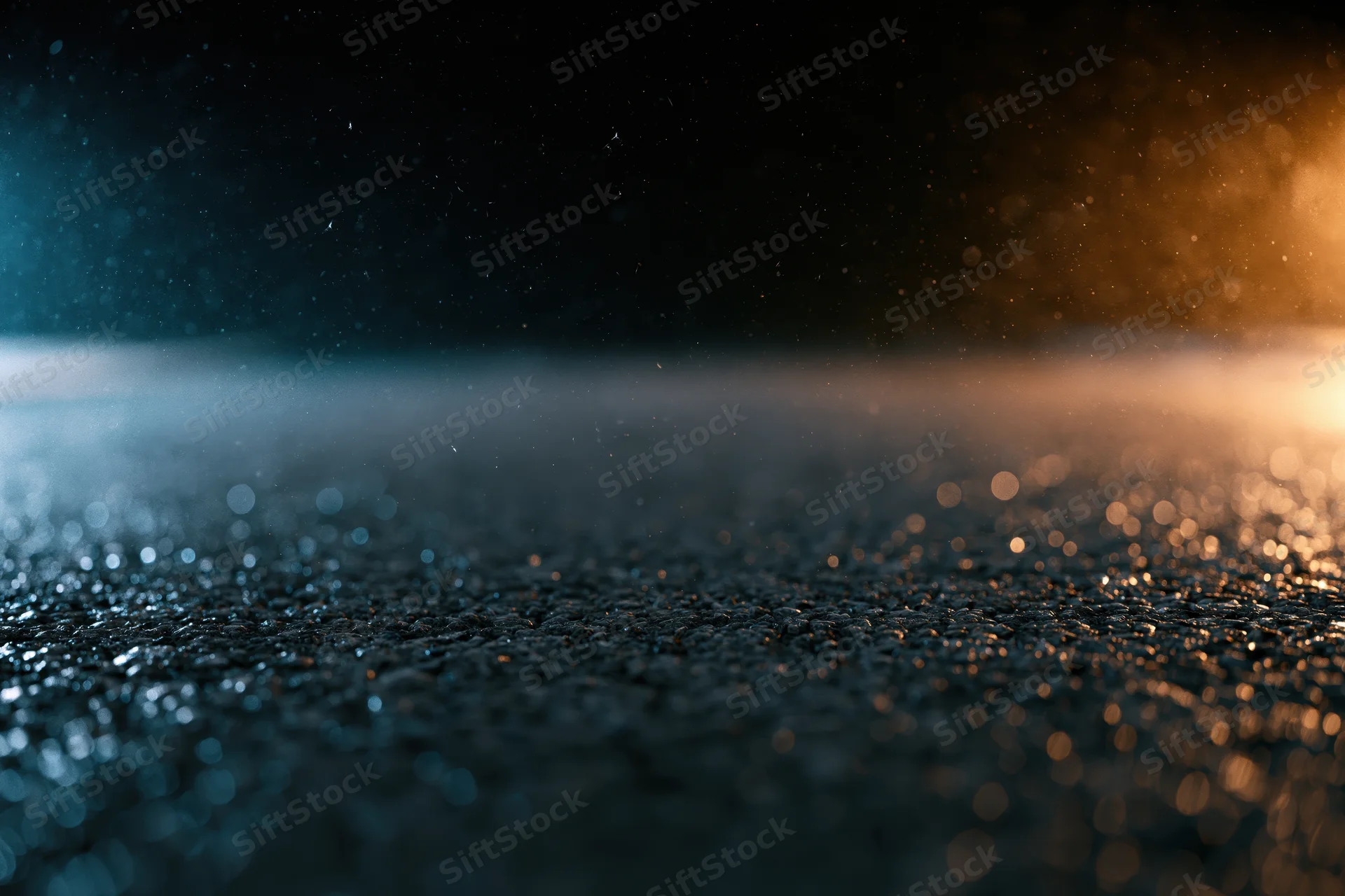 Wet asphalt surface with scattered light reflections and bokeh under dark night sky