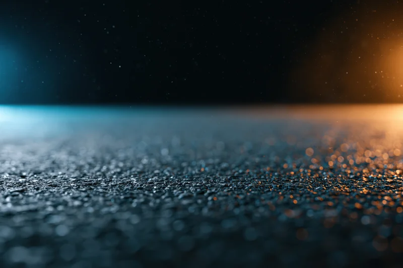 Wet asphalt surface with raindrops and light reflections at night