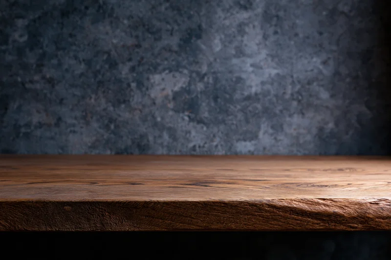 Wooden tabletop surface with dark textured wall background