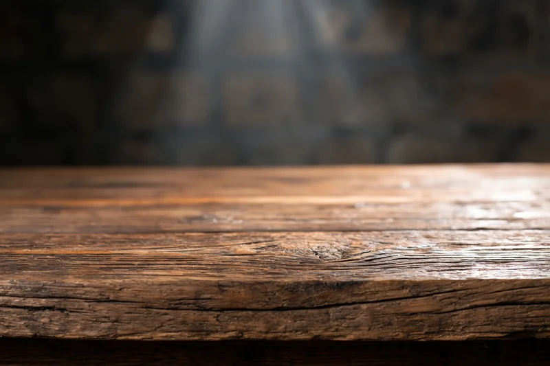 Worn wooden tabletop in a dimly lit rustic interior with blurred background and copyspace