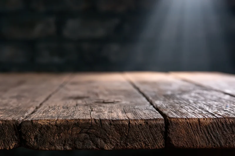 Worn wooden tabletop with dark blurred background and copyspace