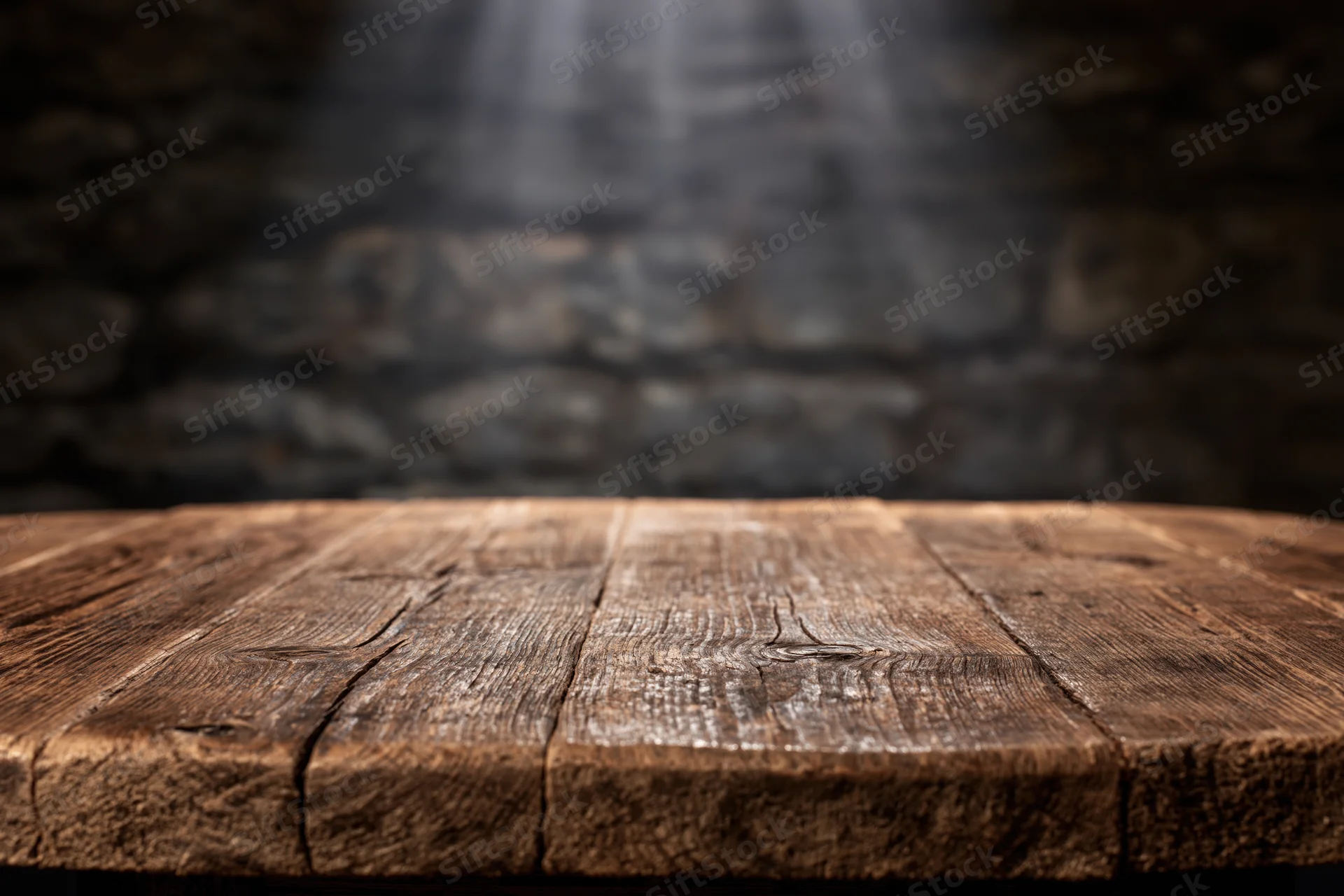 Worn wooden tabletop in front of dark stone wall with spotlight beam