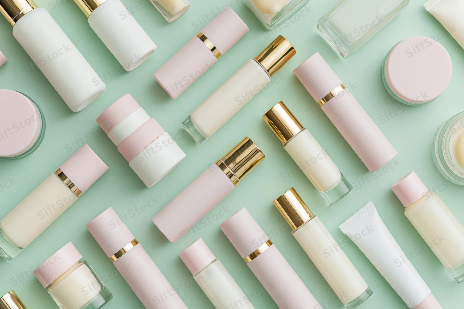 Flat lay of skincare and beauty product bottles arranged on a mint background