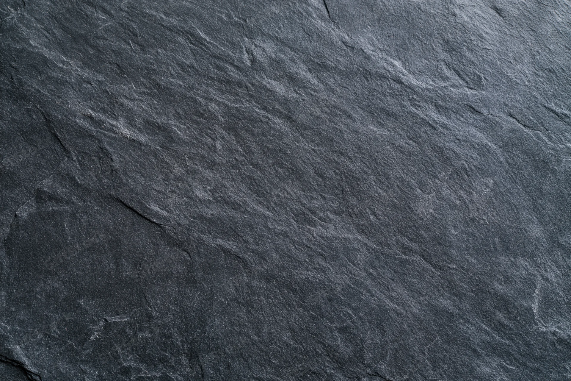 Close-up of dark slate stone surface with natural texture and cracks