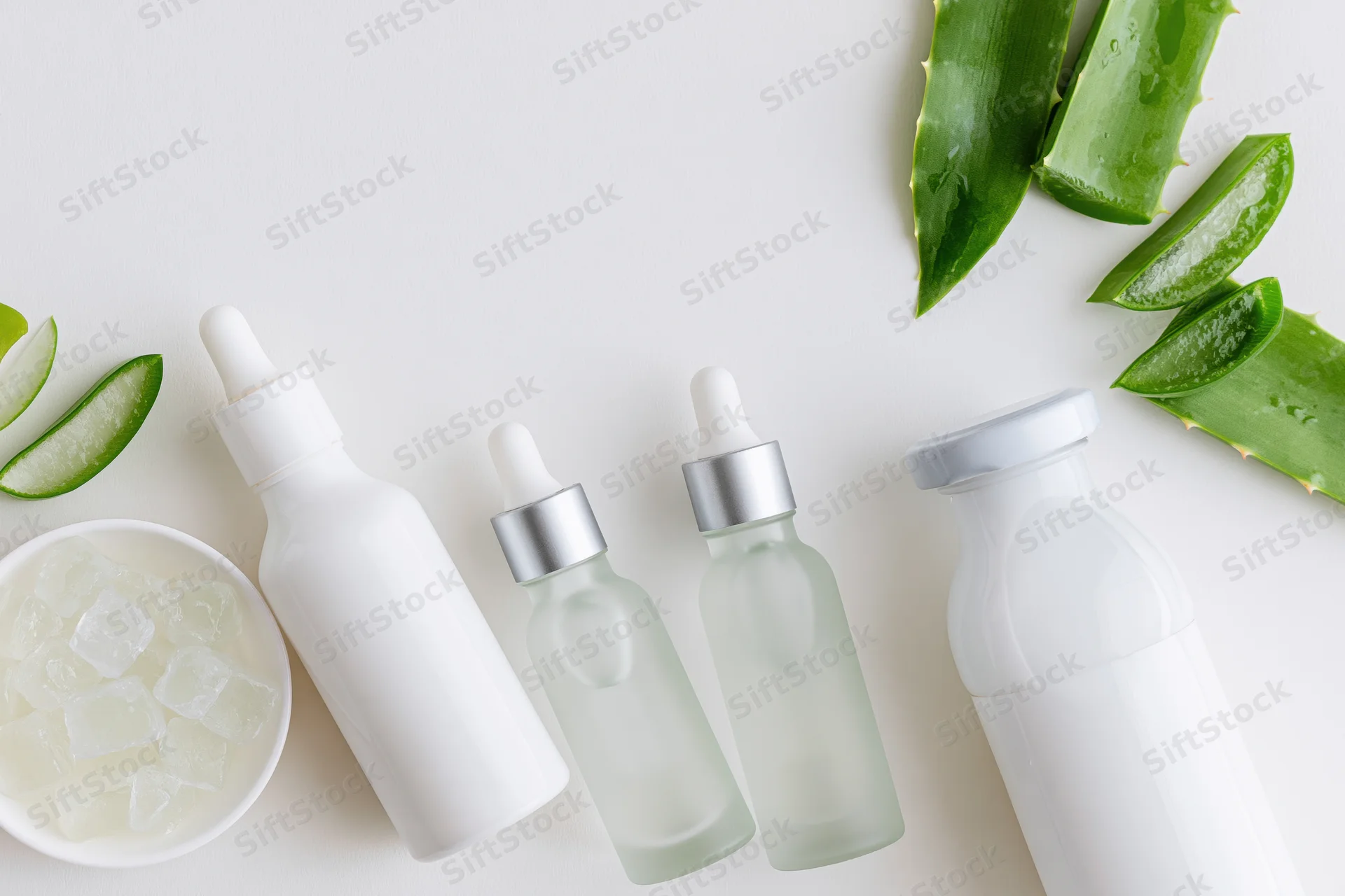 Aloe vera skincare products arranged with fresh leaves and ice cubes on white surface