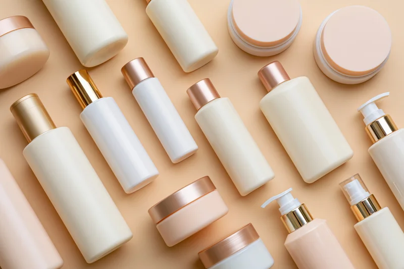Assorted skincare and beauty product containers arranged in flat lay on beige surface