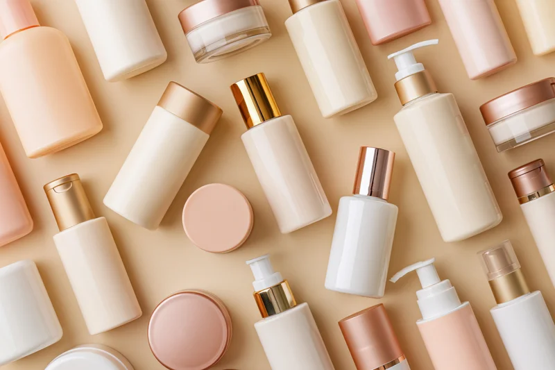 Assorted skincare and beauty product containers arranged in flat lay on beige background