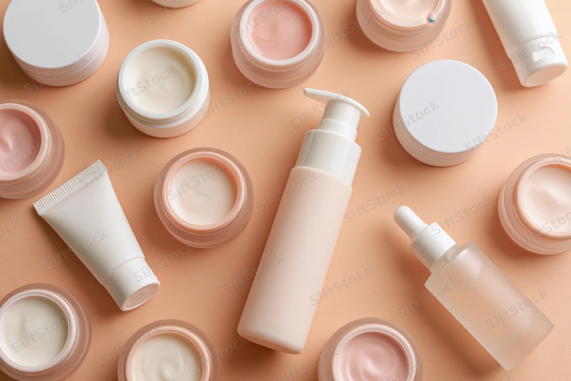Assorted skincare products arranged in flat lay on peach background