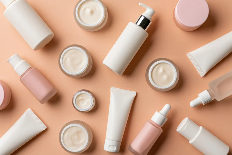 Assorted skincare products arranged in flat lay on peach background