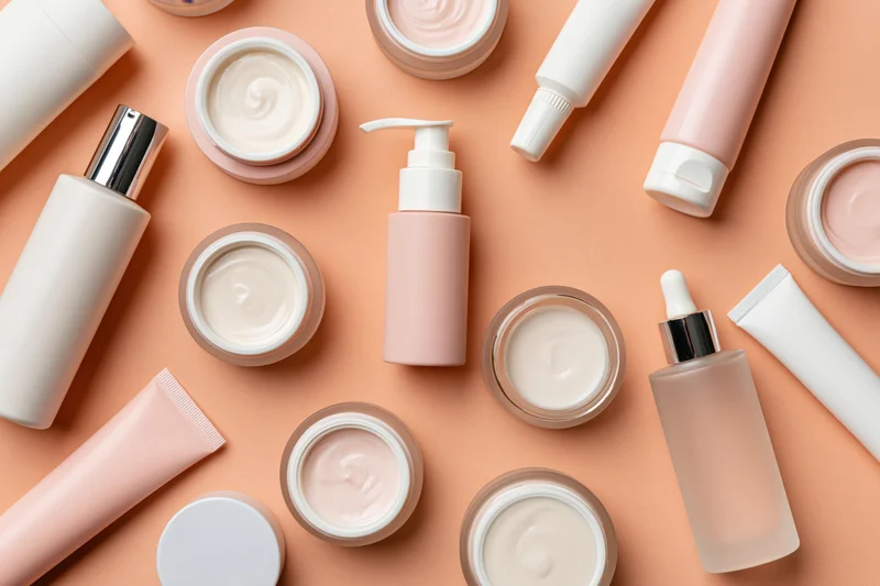 Assorted skincare products arranged in flat lay on peach background