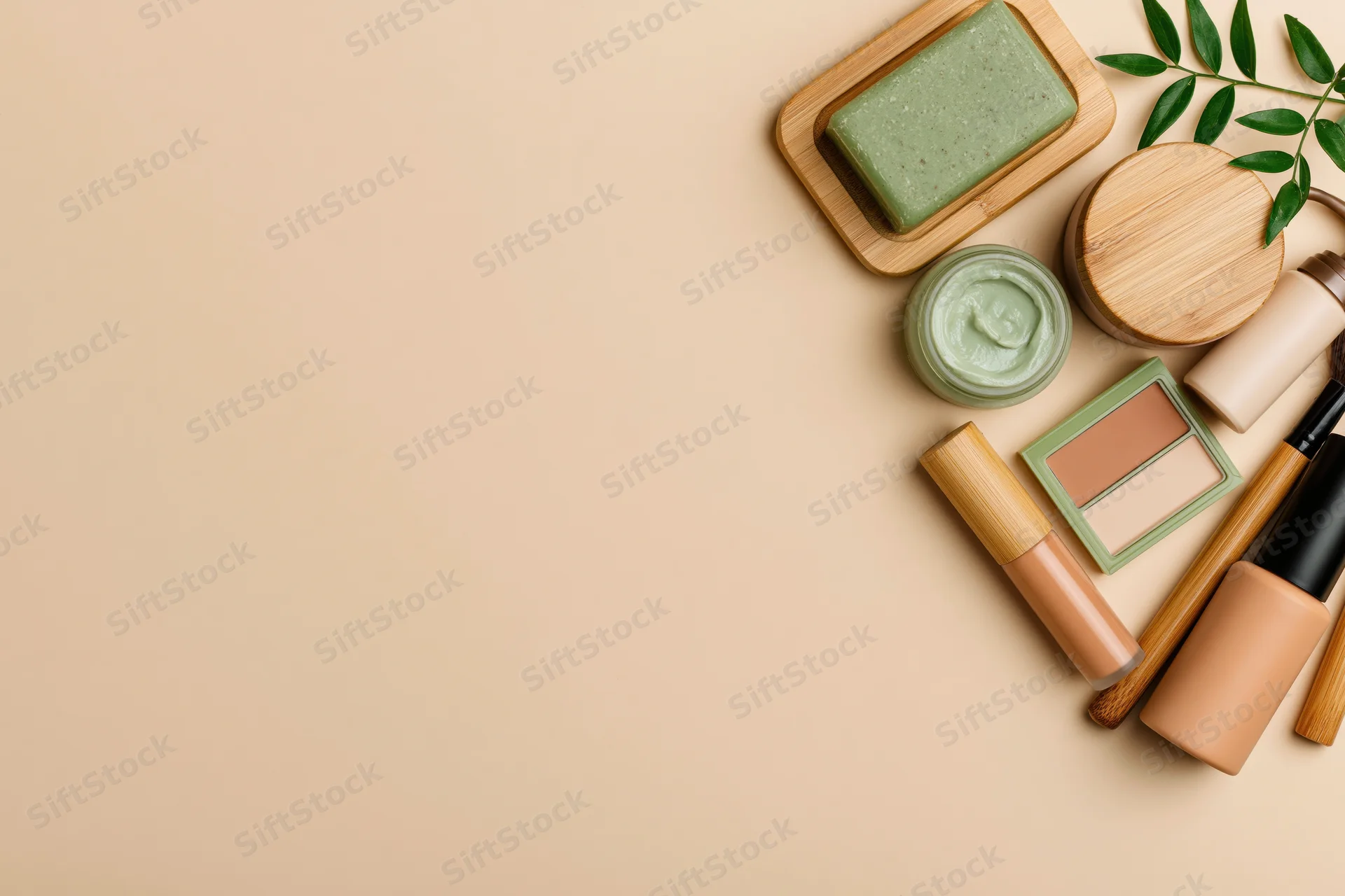 Eco-friendly skincare and makeup products arranged in flat lay on beige background with bamboo and leaf accents