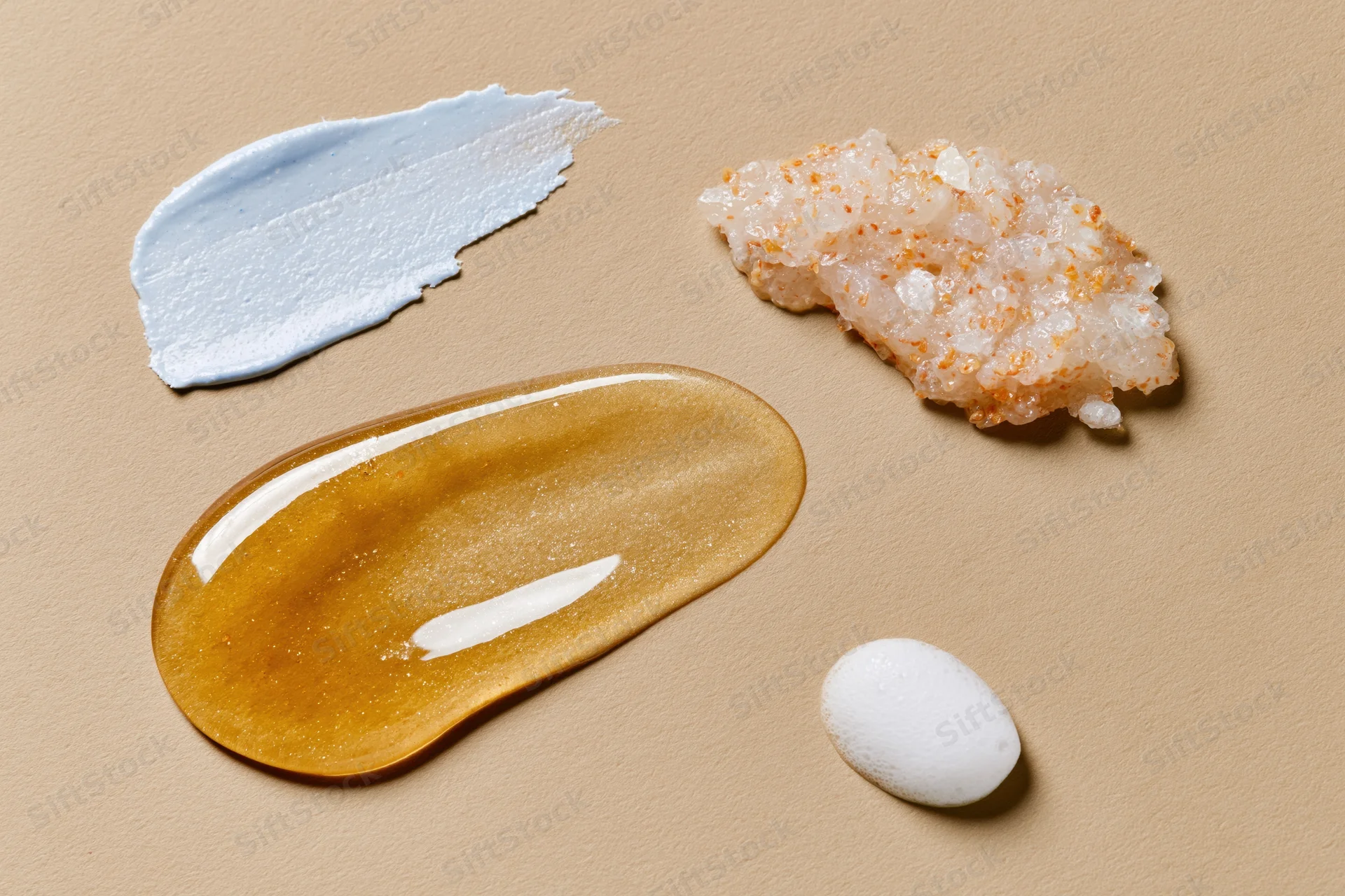 Four skincare product textures arranged on beige paper in flat lay view