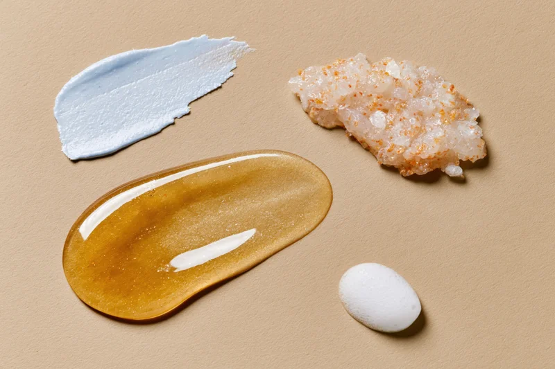 Four skincare product textures arranged on beige paper in flat lay view