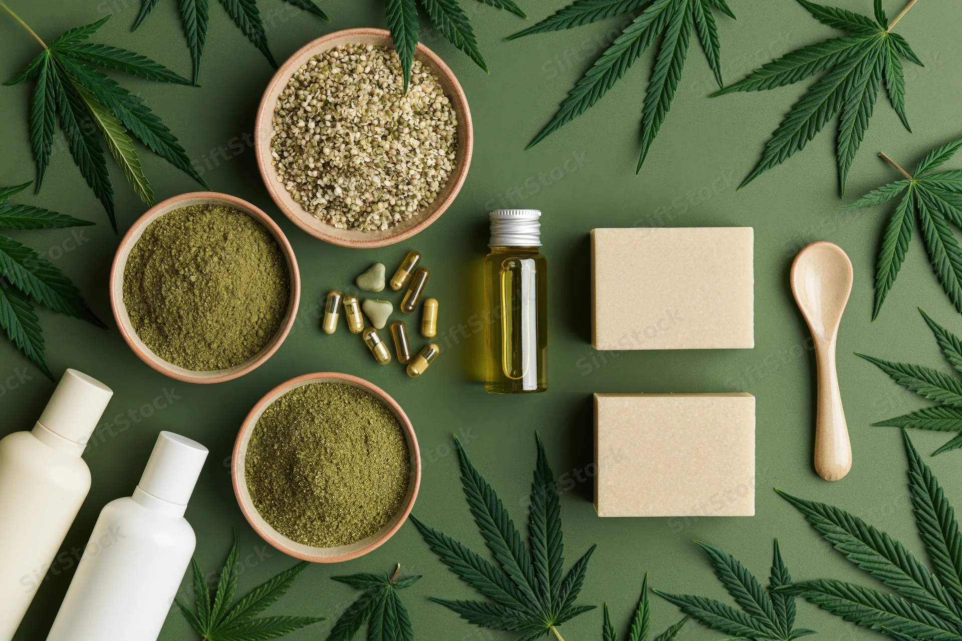 Hemp wellness products arranged in flat lay on green background with leaves and containers