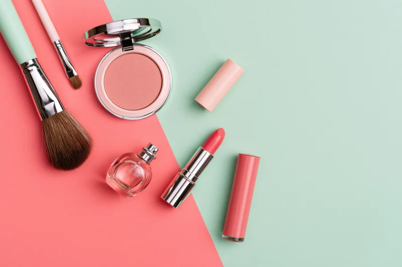 Makeup products arranged on a split pink and mint background