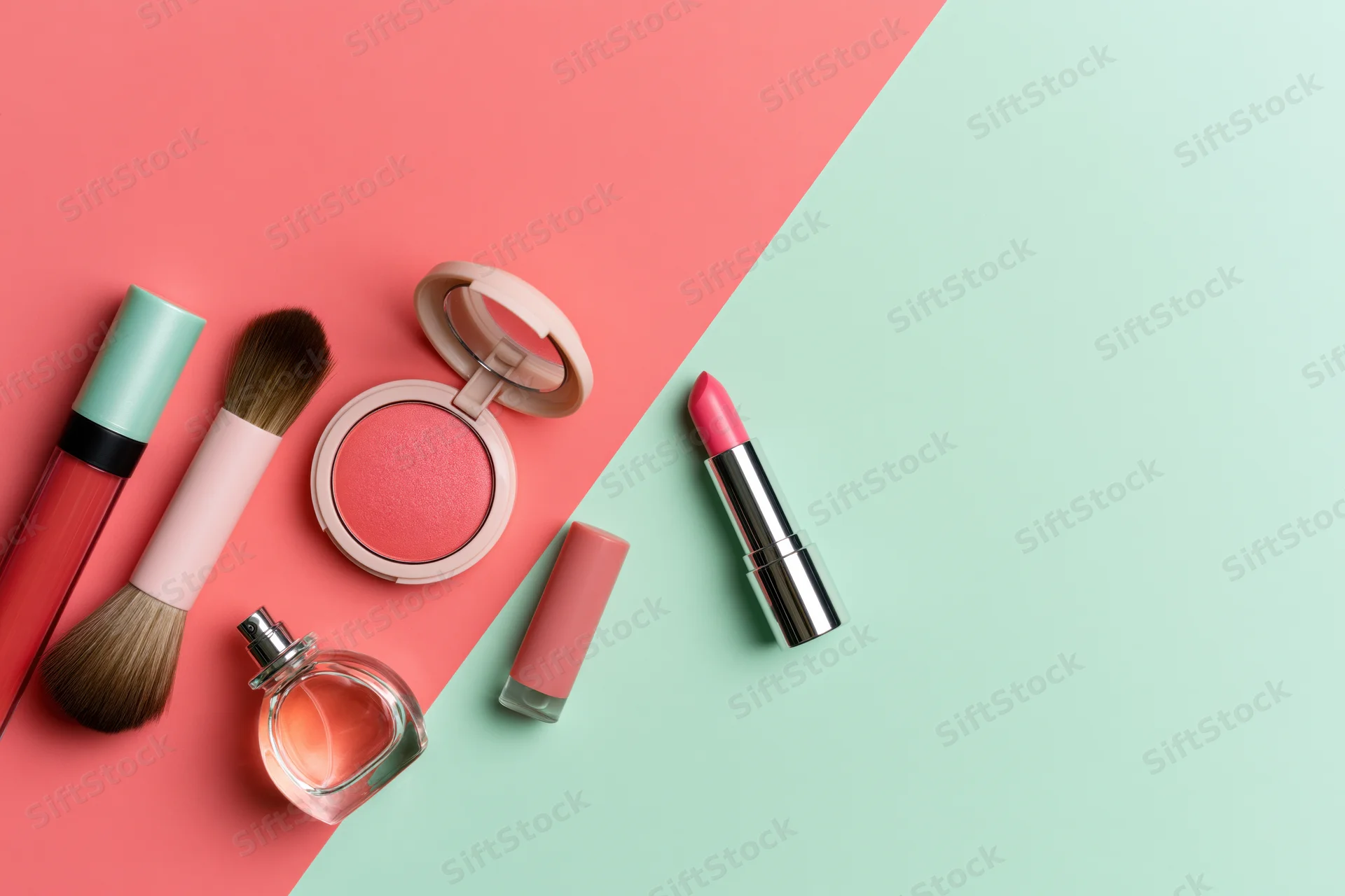 Makeup products arranged in flat lay on split pink and mint background
