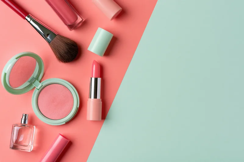 Makeup products arranged on a split pink and mint background with copyspace
