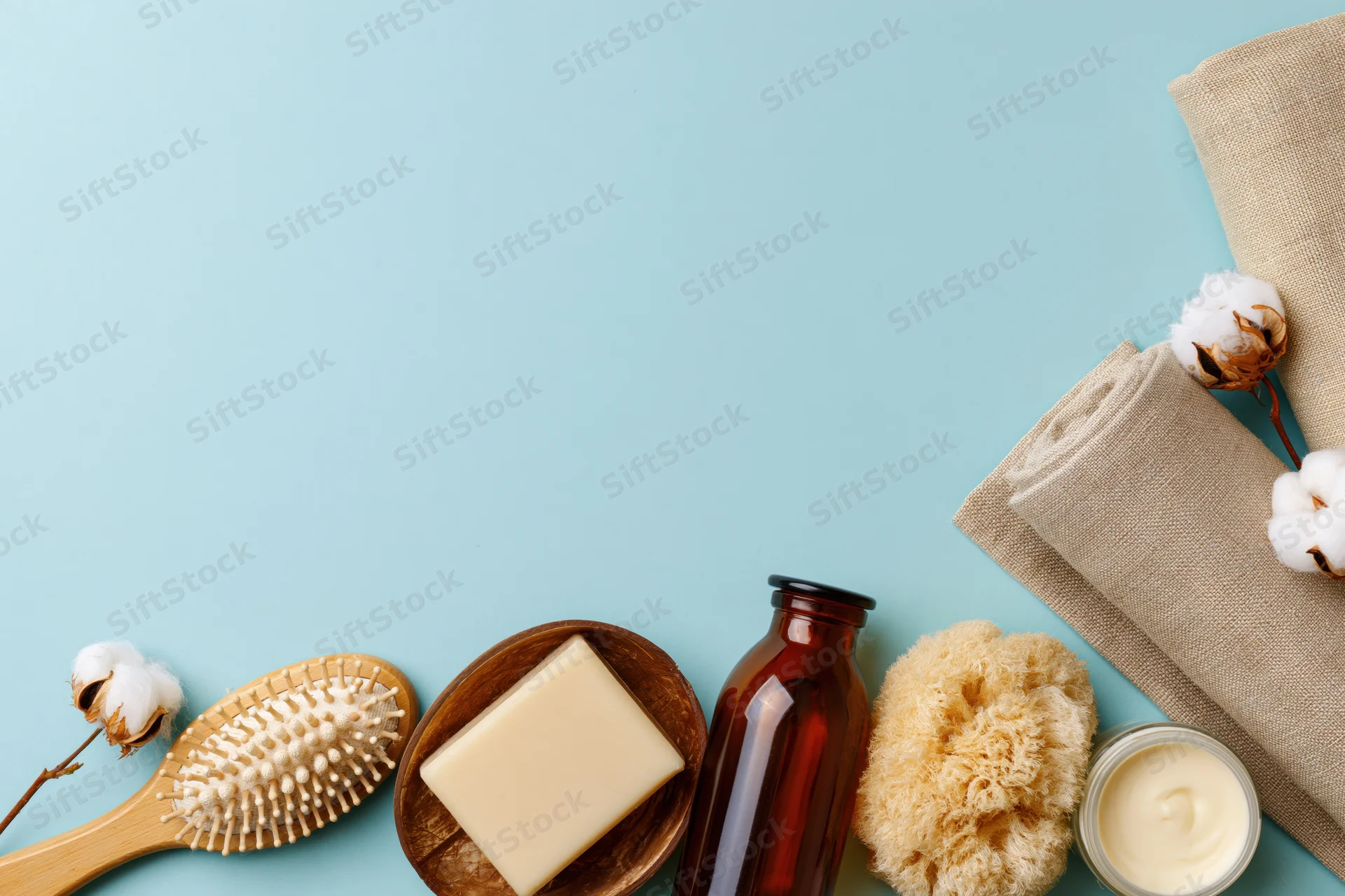 Natural skincare and bath products arranged in flat lay on blue background with copyspace