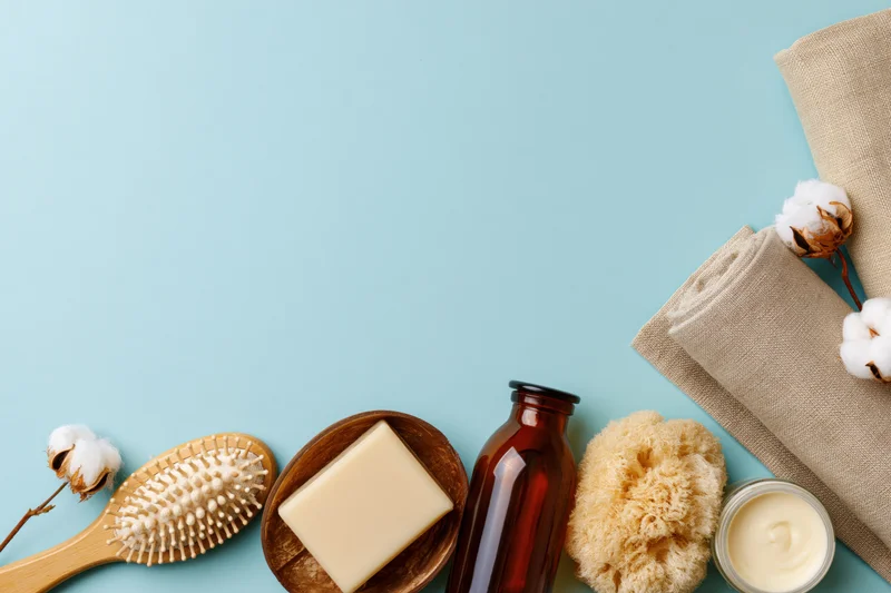 Natural skincare and bath products arranged in flat lay on blue background with copyspace