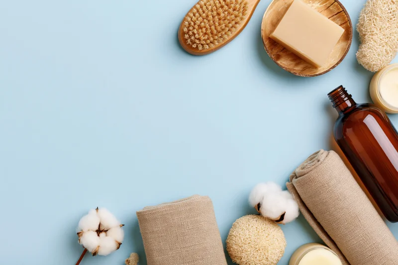 Natural skincare and bathroom products arranged in flat lay on blue background with copyspace