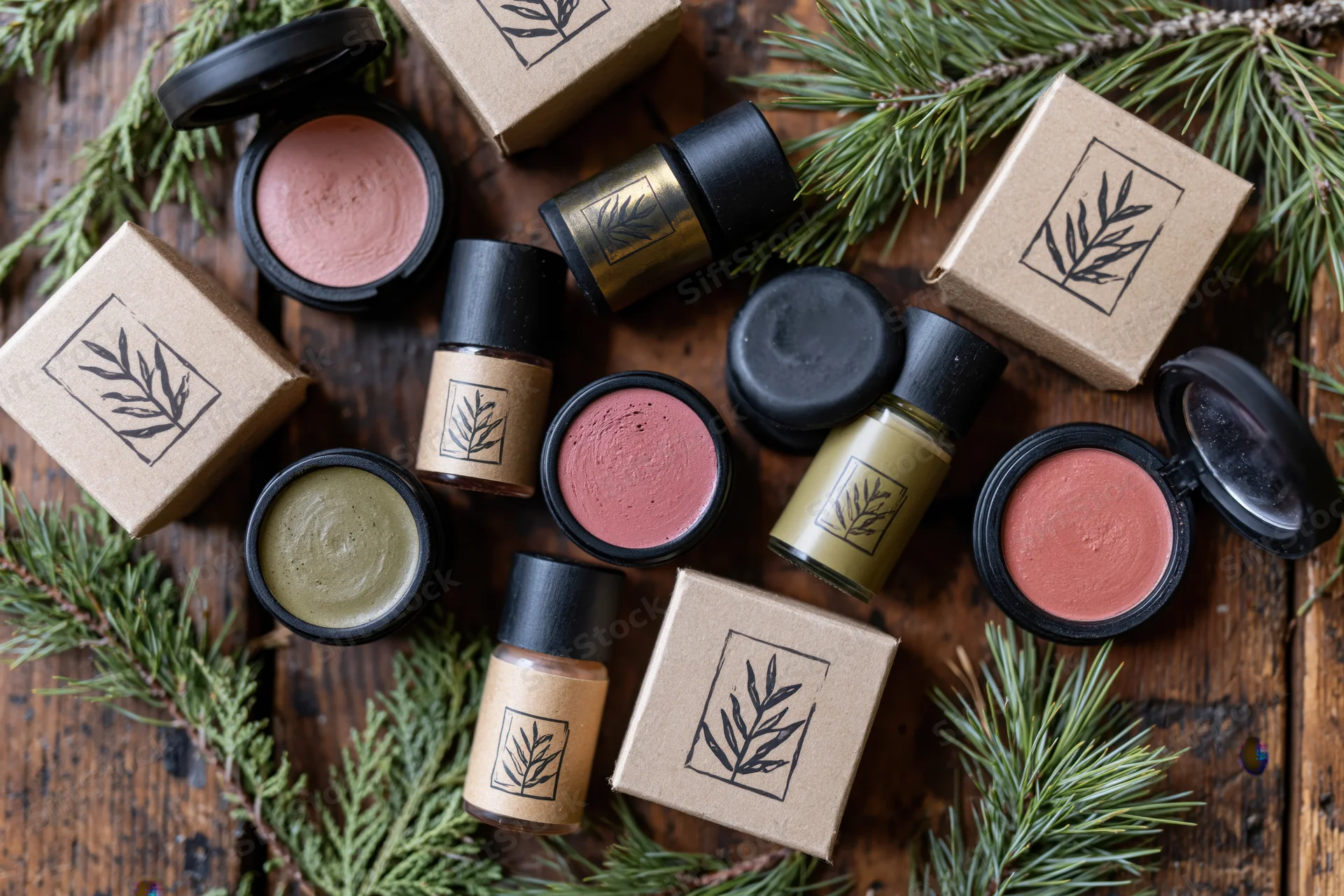 Natural cosmetics products arranged with evergreen sprigs on wooden surface
