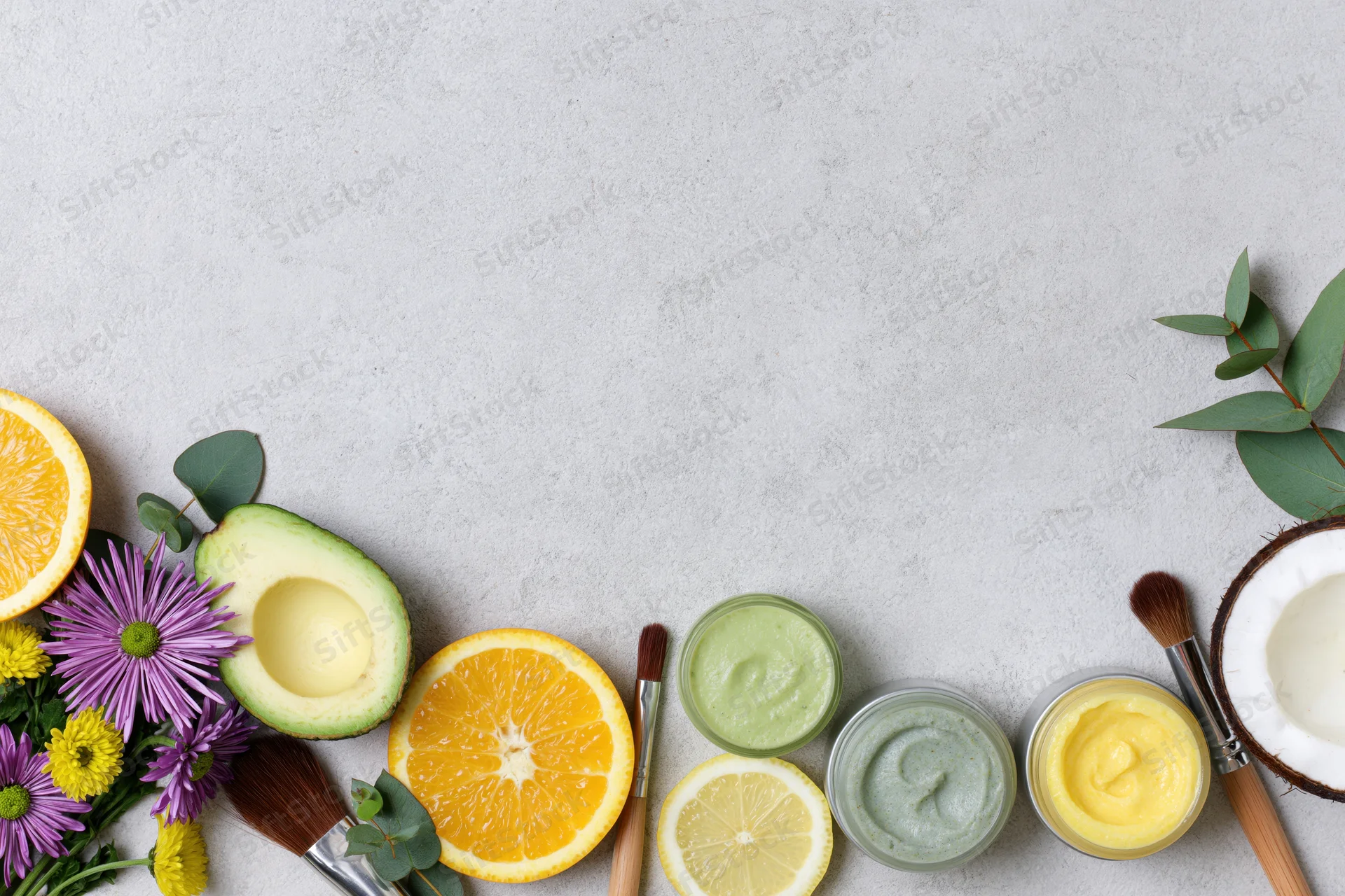Natural skincare ingredients and products arranged in flat lay on gray surface with copyspace