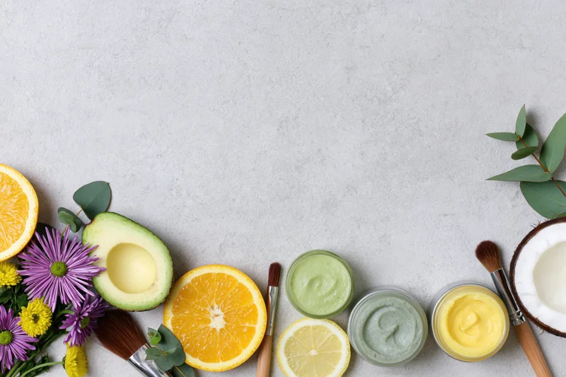 Natural skincare ingredients and products arranged in flat lay on gray surface with copyspace