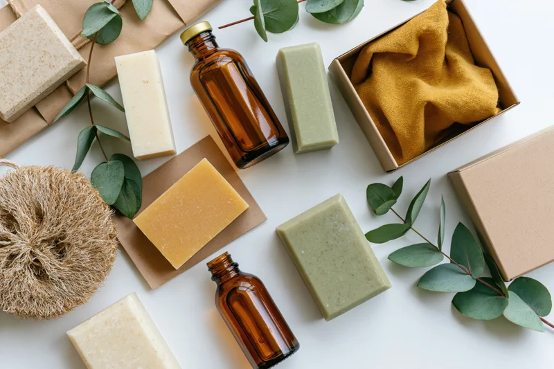 Natural skincare products arranged in flat lay on white surface with eucalyptus leaves and eco packaging