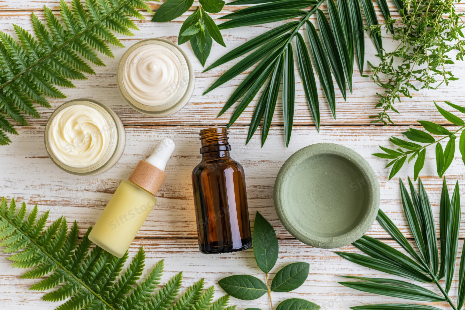 Natural skincare products arranged with green leaves on a wooden surface