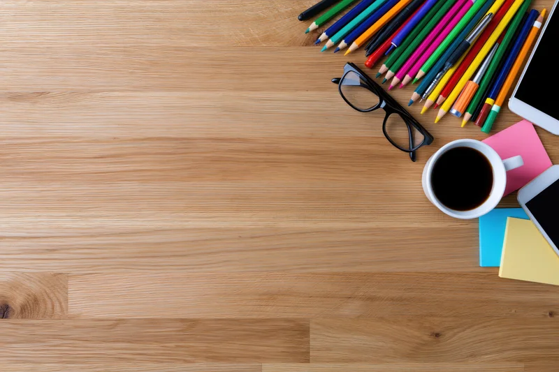 Wooden desk with office and art supplies arranged in corner, flat lay overhead view