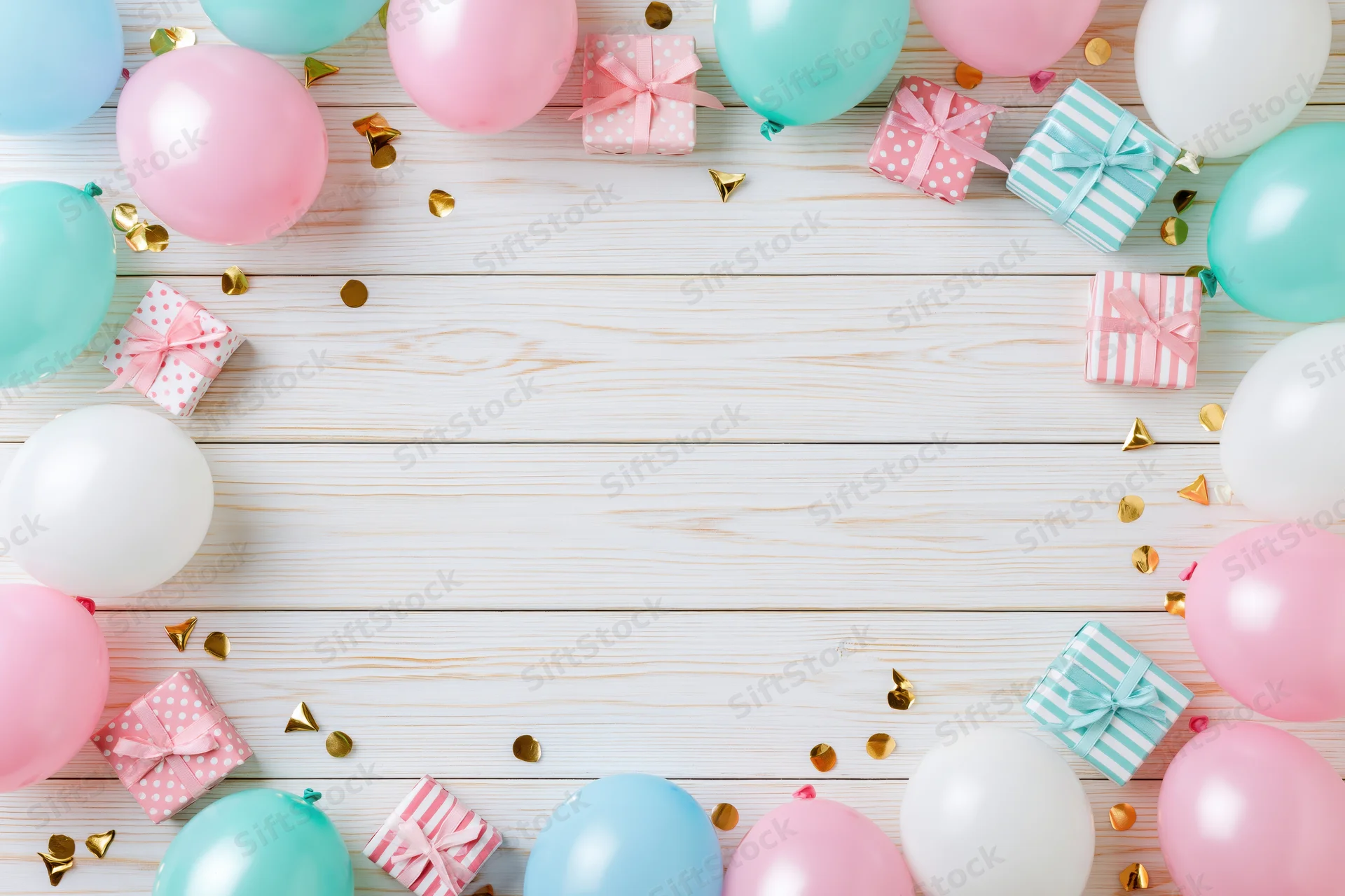 Pastel balloons and gift boxes arranged in a frame on a white wooden table with copyspace in the center