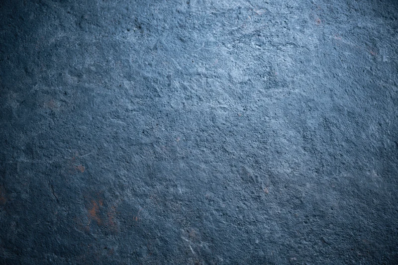Textured concrete wall surface with rough gray-blue finish and subtle lighting variation