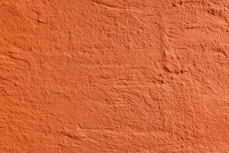 Textured stucco wall painted in deep burnt orange, showing rough plaster surface