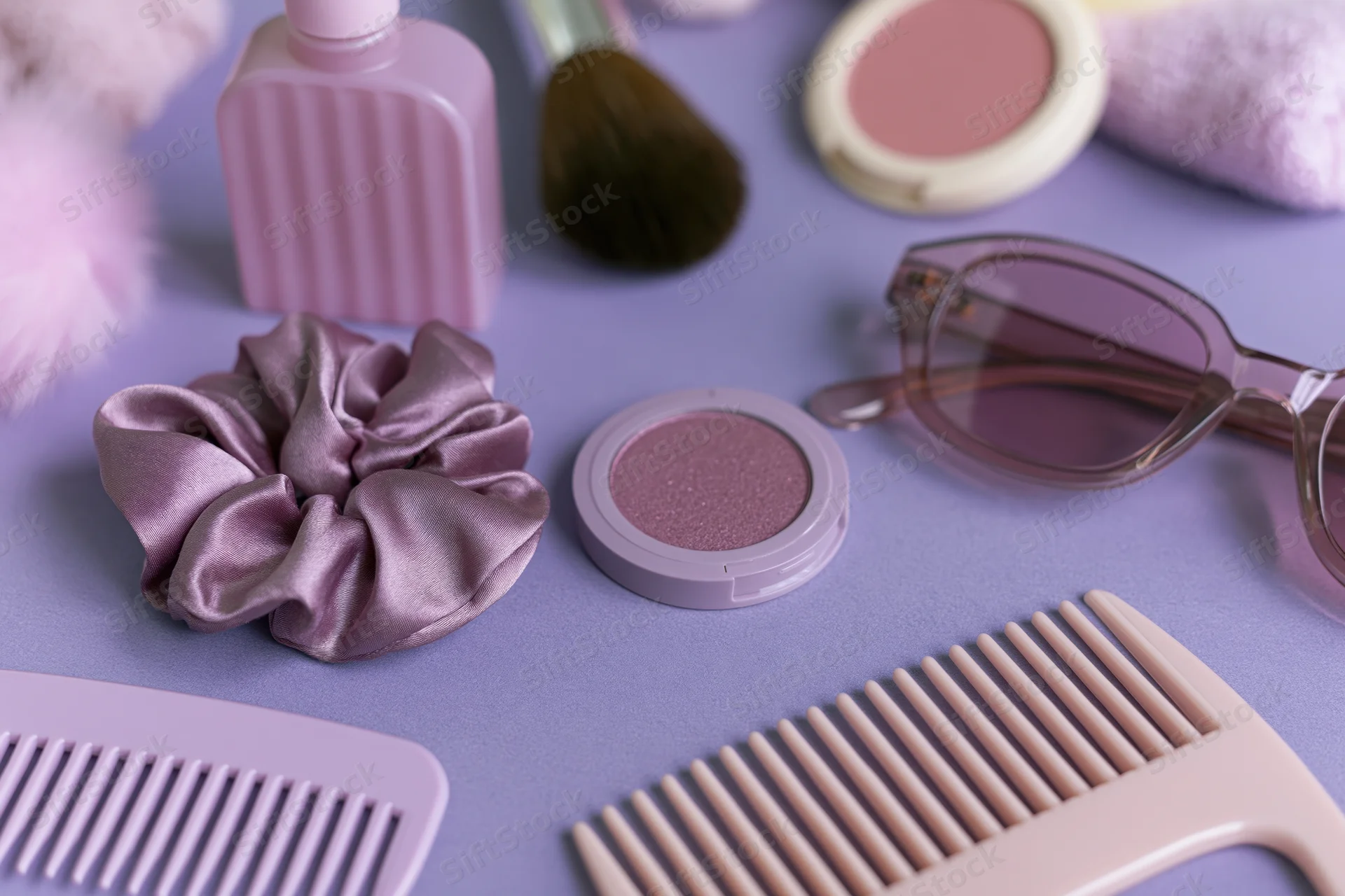 Beauty accessories arranged in flatlay on purple surface with combs, scrunchie, sunglasses and makeup products