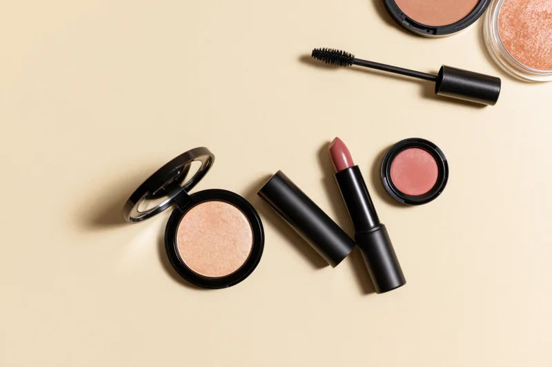 Makeup products arranged in flatlay on beige background