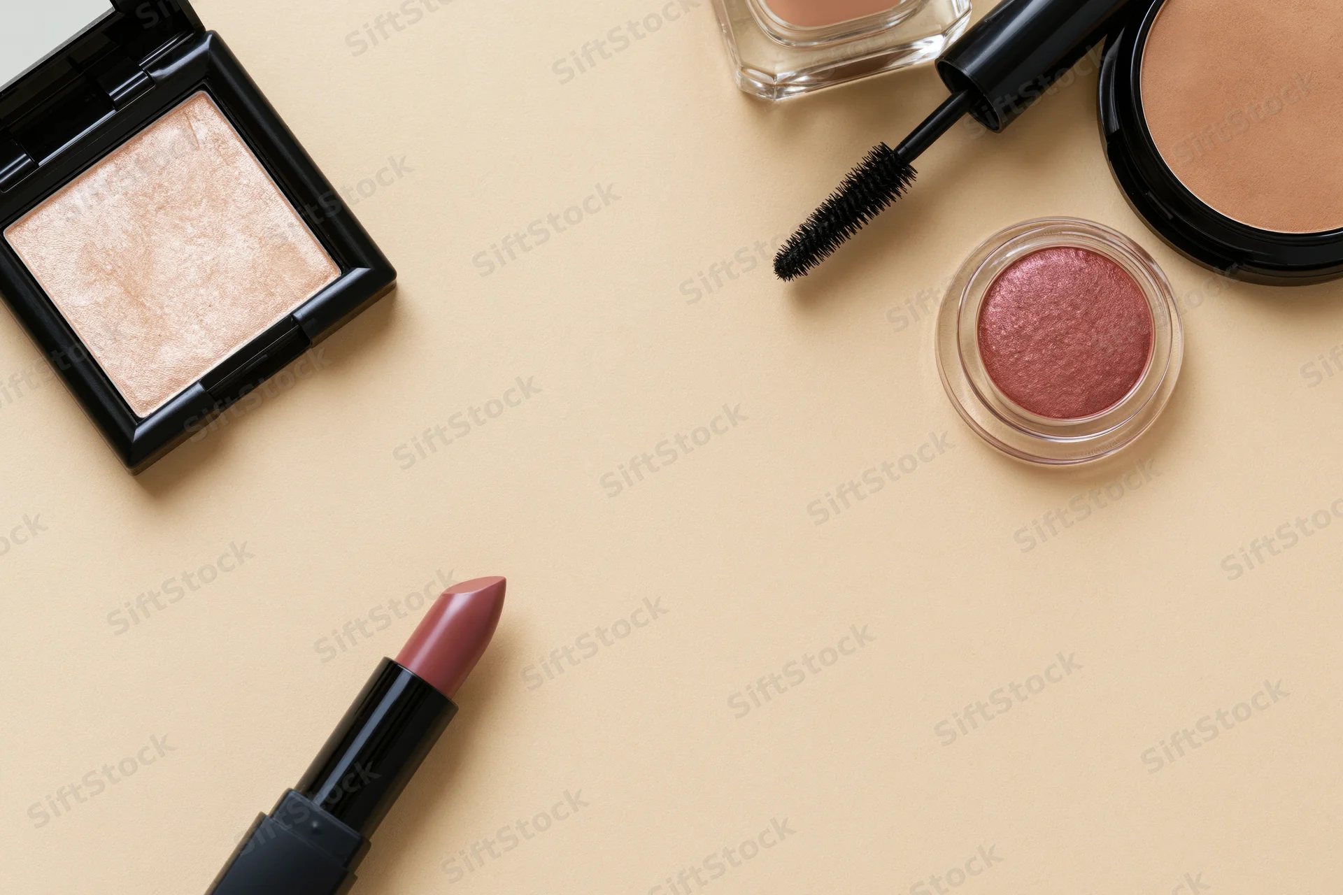 Makeup products arranged in flatlay on beige surface with copyspace