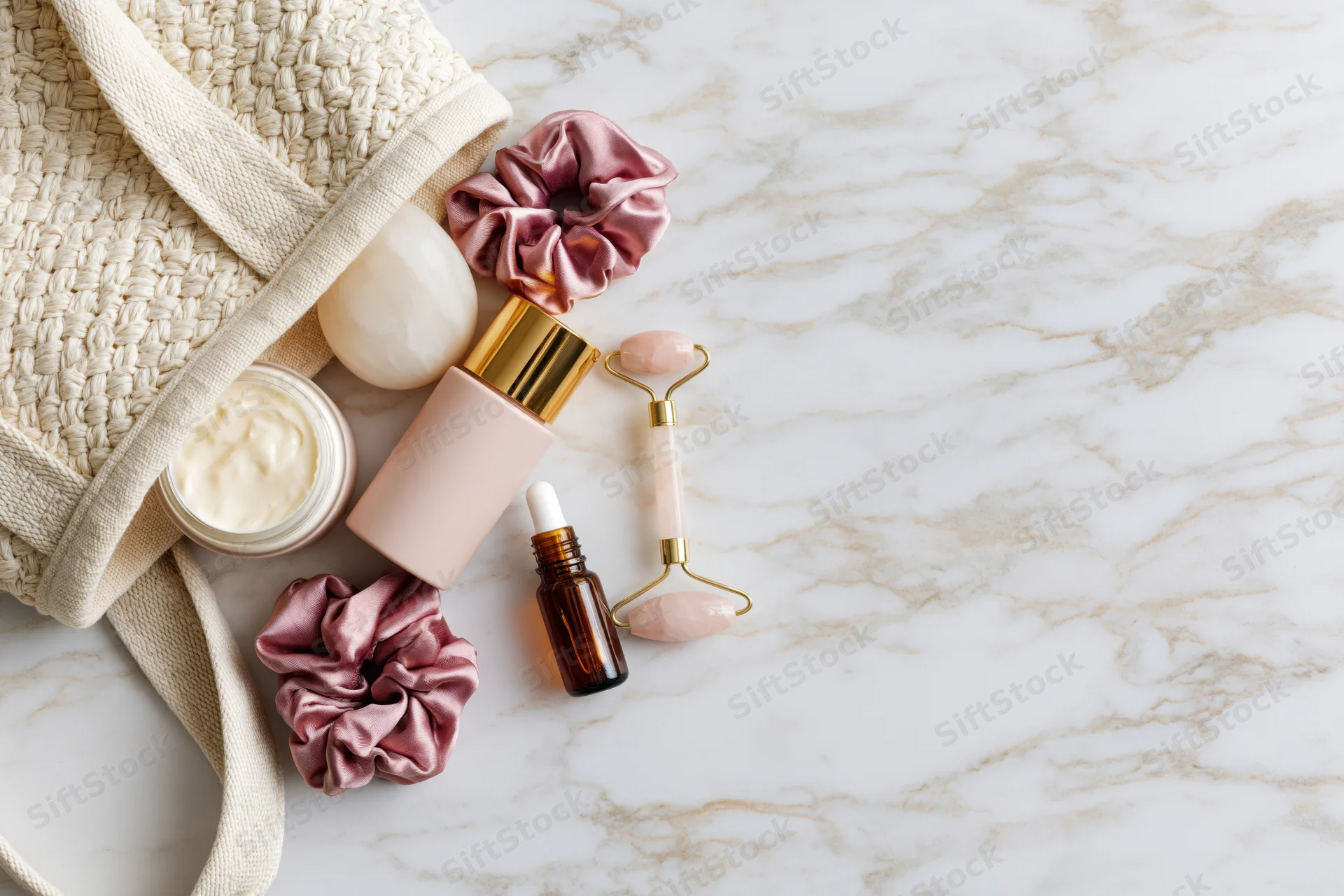 Skincare products spilling from an open woven bag on marble surface