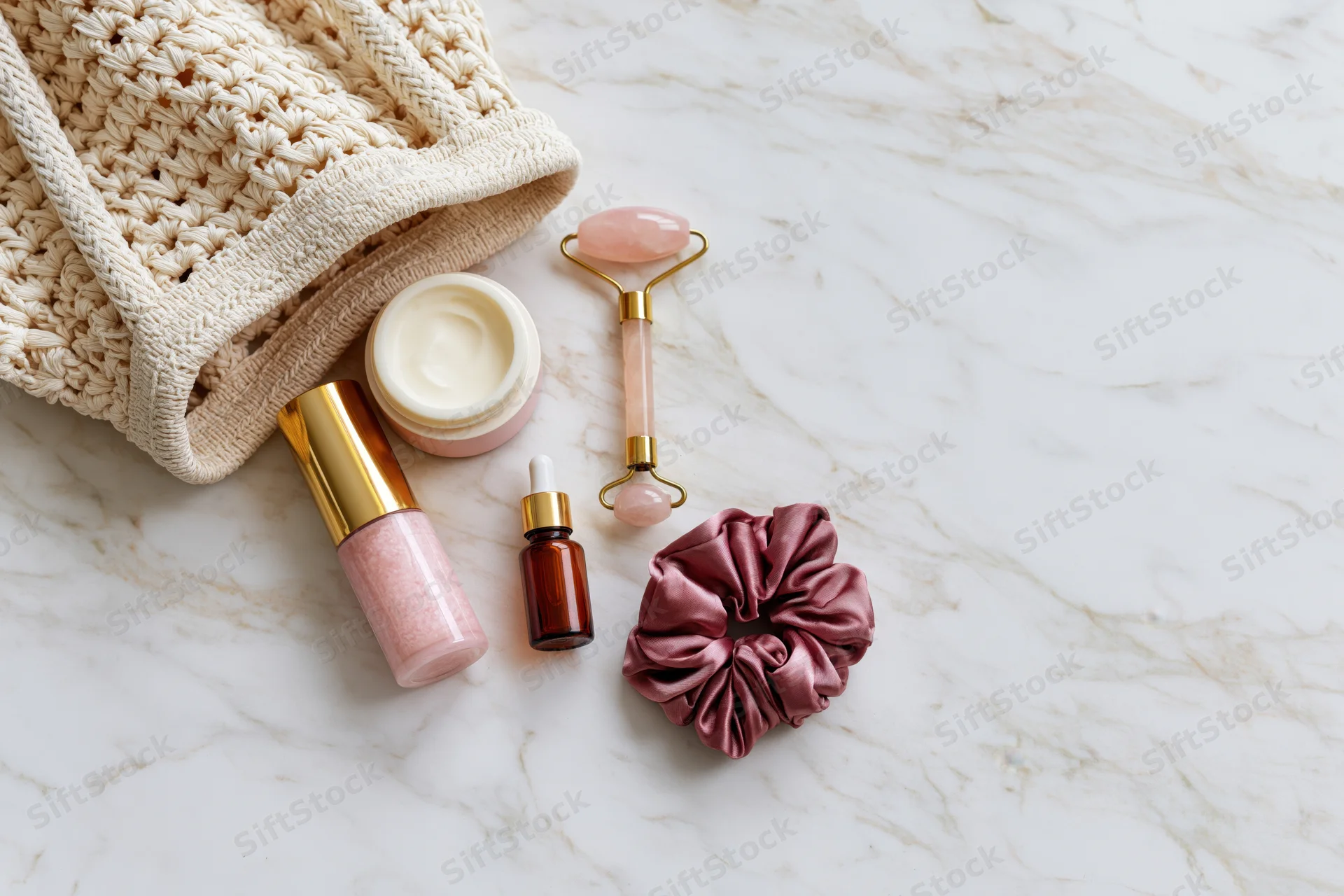 Skincare products and accessories arranged on marble surface with copyspace