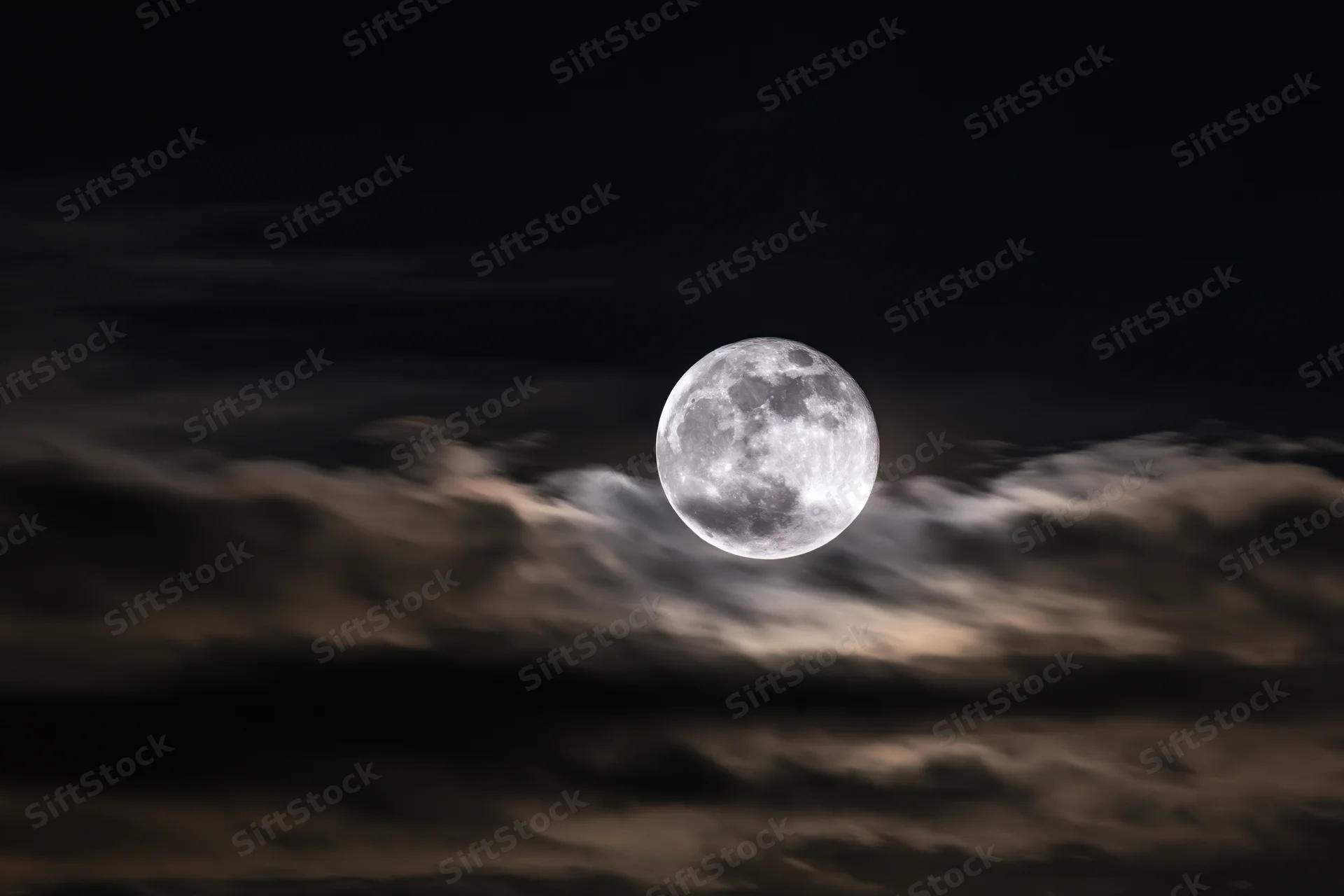 Full moon glowing above layered clouds in dark night sky