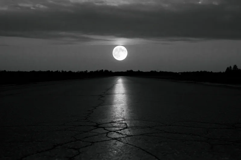 Full moon rising over a cracked asphalt road at night, reflecting light on the dark surface