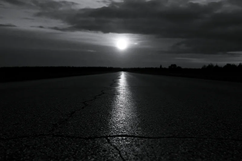 Full moon rising low over a cracked empty asphalt road at night