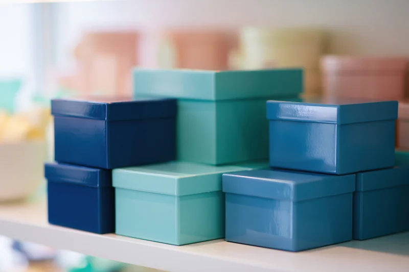 Glossy teal and deep blue gift boxes stacked on a white shelf in a retail display
