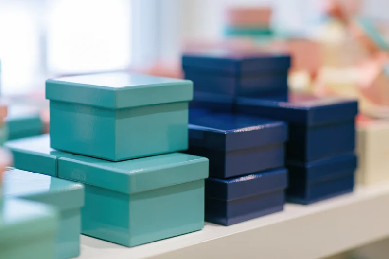 Glossy teal and blue gift boxes stacked on a store shelf for display