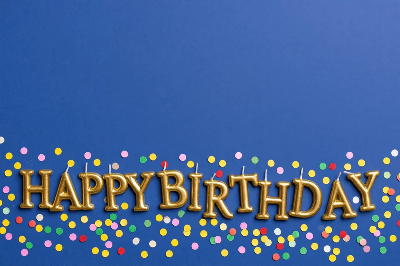 Gold lettered birthday candles HAPPY BIRTHDAY on blue background
