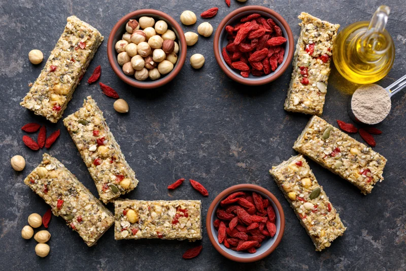 Granola bars and ingredients arranged in a circular frame on dark stone surface