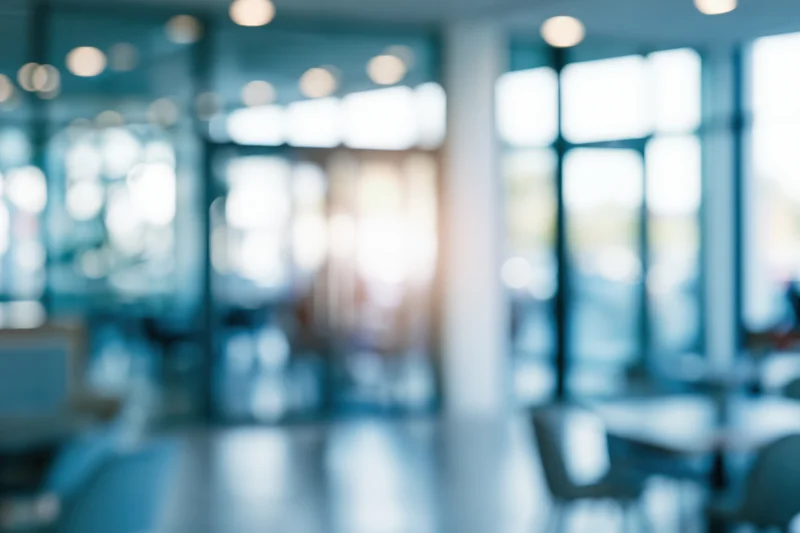 Blurred interior of a modern office lobby with glass walls and soft lighting